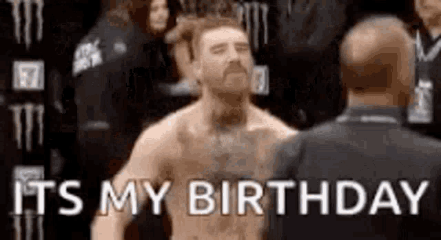 a man without a shirt is standing next to a man in a suit and says `` it 's my birthday '' .