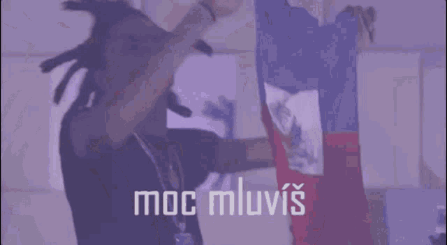 a man with dreadlocks is standing in front of a flag and the words moc mluvis are above him