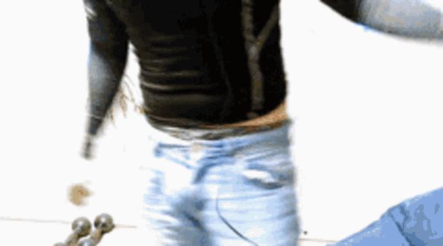 a man in a black shirt and blue jeans is standing on a white surface with his arms outstretched