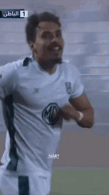 a man in a green and white soccer jersey is laughing with his mouth open