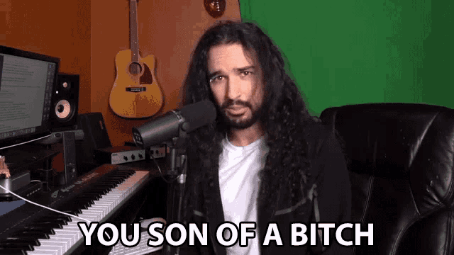 a man with long hair and a beard says you son of a bitch in front of a microphone