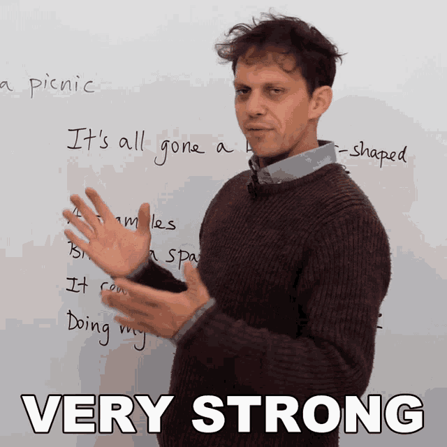 a man stands in front of a white board that says very strong