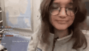 a girl wearing glasses and a jacket is smiling and looking at the camera .
