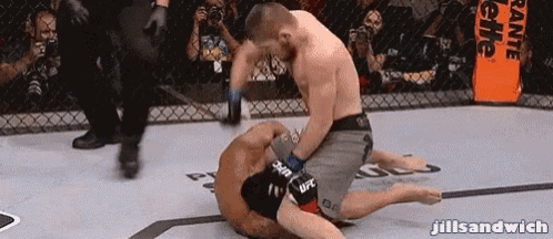 a man in a ufc shorts is wrestling another man in a ring