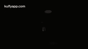 a woman with long blonde hair is standing in a dark room with a glowing circle around her .