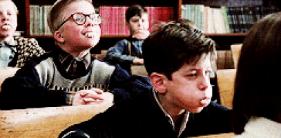 a boy with glasses is sitting in a classroom with other children