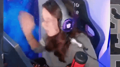 a woman wearing headphones is sitting in front of a computer and dancing .