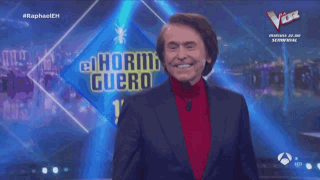 a man in a suit stands in front of a sign that says el horni guero 15 anos