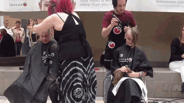 a woman is getting her hair cut in front of a leucan banner