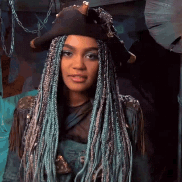a woman with blue braids is wearing a hat
