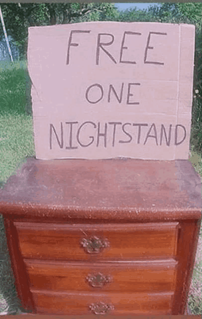 a cardboard sign on top of a wooden nightstand that says free one nightstand