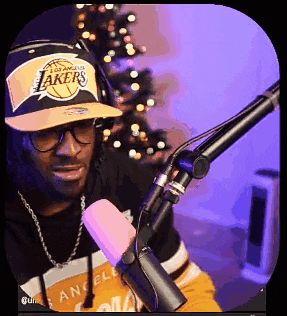 a man wearing a lakers hat and headphones is sitting in front of a microphone .