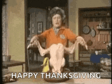 a woman is holding a dead turkey over a table and says `` happy thanksgiving '' .