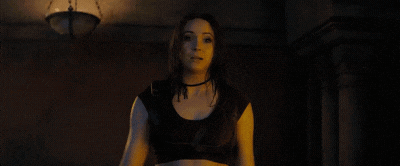 a woman is standing in a dark room with the word boobs in pink