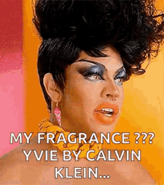 a drag queen wearing a wig and earrings is talking about her fragrance .