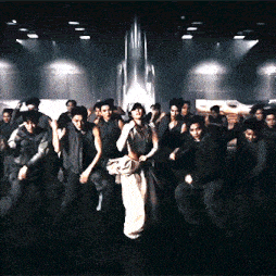 a group of people dancing in a dark room with a rocket in the background