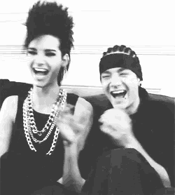 a man and a woman are sitting on a couch and laughing .