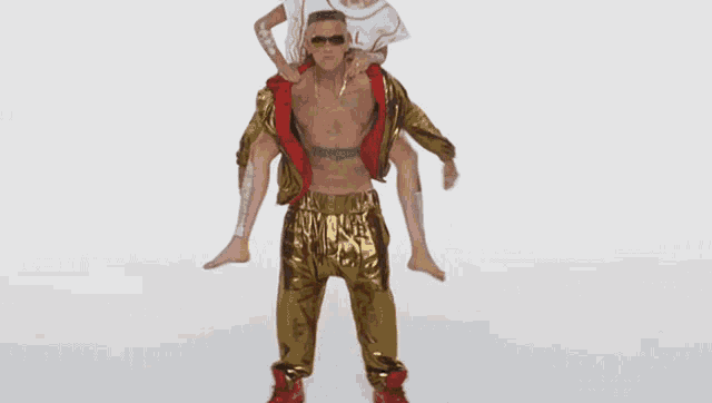 a man is carrying a woman on his shoulders in a gold outfit