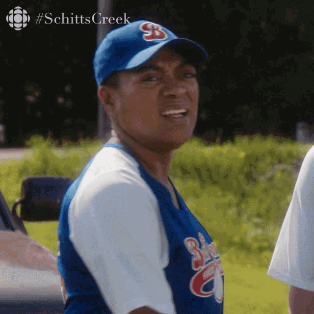 a man wearing a baseball cap with the letter b on it is making a funny face