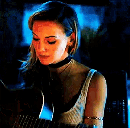 a woman wearing a choker is holding a guitar