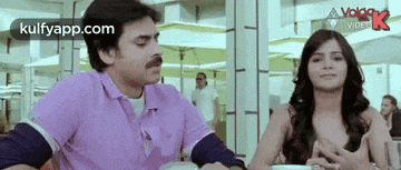 a man and a woman are sitting at a table and talking to each other .