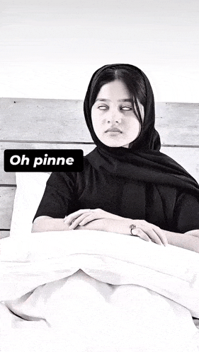 a woman in a black scarf is laying in bed with a sign that says oh pinne on it