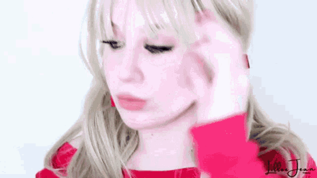 a woman with blonde hair is wearing a red sweater and red earrings