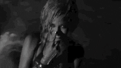 a black and white photo of a woman in a bra smiling .