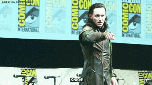 a man is kneeling in front of a comic con banner .