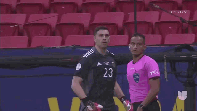 a soccer player wearing a number 23 jersey is standing next to another player in a pink shirt .
