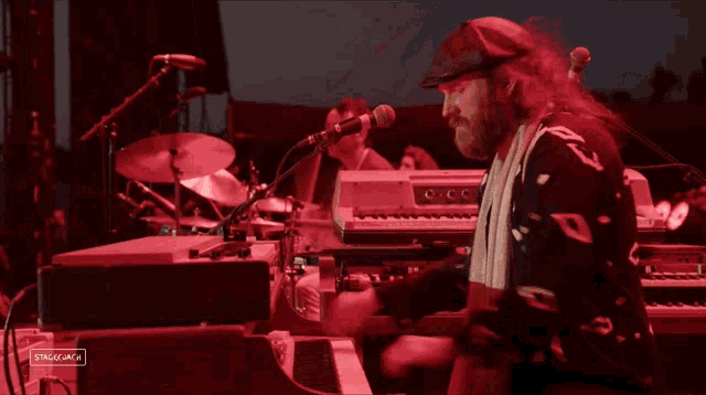 a man playing a keyboard in front of a stage that says stageshack