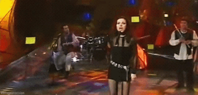 a woman singing into a microphone with a band behind her .