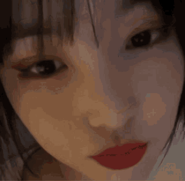 a close up of a woman 's face with red lipstick and black eyes .