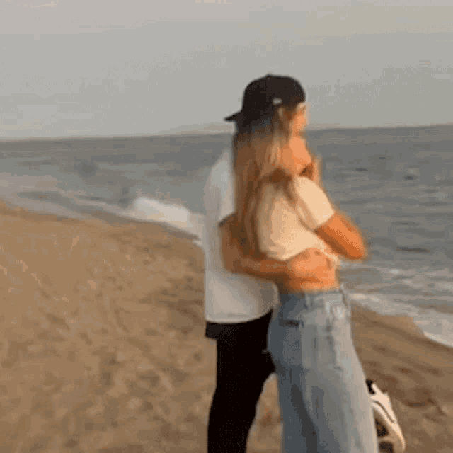 a man and a woman are hugging on a beach .