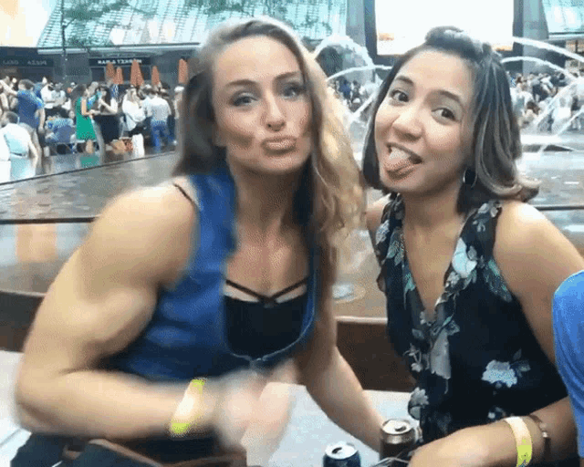 a woman sticking her tongue out next to another woman with a can of soda