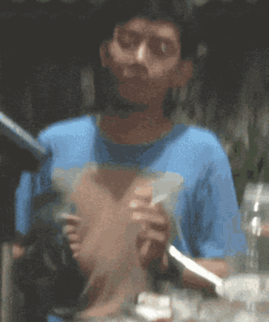 a blurry picture of a man in a blue shirt holding a knife and fork
