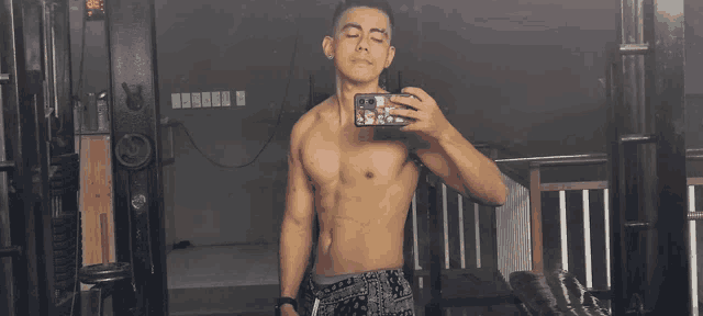 a shirtless man taking a picture of himself in a mirror