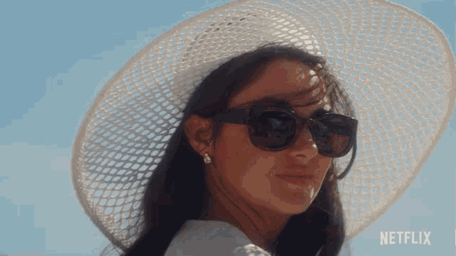 a woman wearing sunglasses and a white hat with netflix written on the bottom right