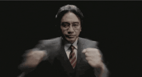 a man in a suit and tie is standing in a dark room with smoke coming out of his mouth .
