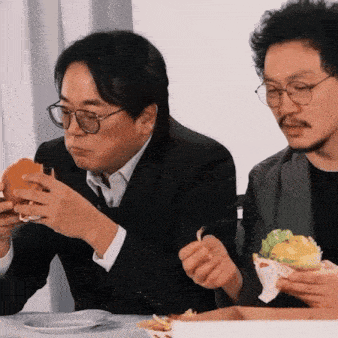 a man in a suit and tie is eating a hamburger