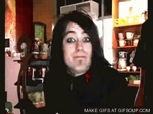 a man with long black hair is making a funny face in a kitchen with the words make gifs at gifsoup.com