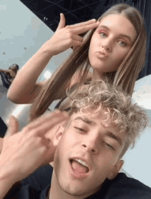 a man and a woman are posing for a picture and the woman is pointing her finger at the man 's face