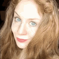 a woman with red hair and blue eyes is smiling for the camera .
