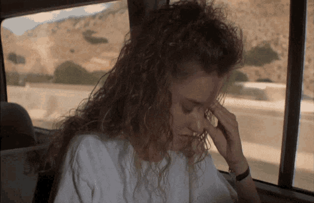 a woman with curly hair is sitting in a car