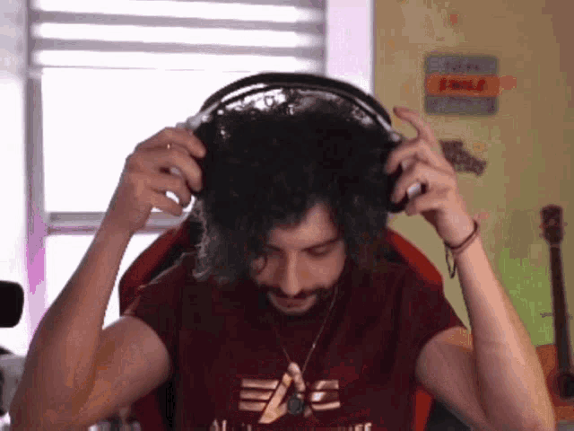 a man wearing headphones and a maroon shirt that says eae