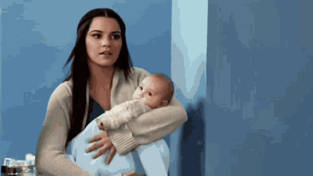 a woman is holding a baby in her arms and looking at it