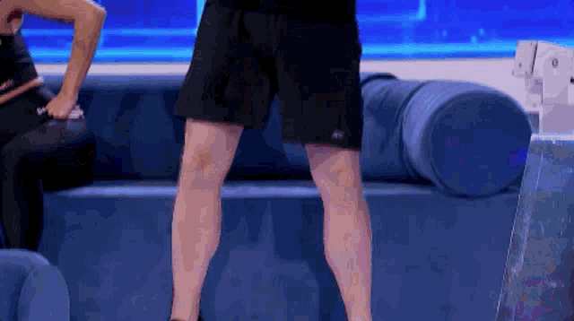 a man in black shorts is standing on a blue couch