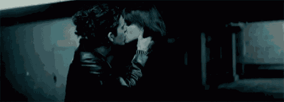 a man and a woman are kissing in a dark room in a dark room .