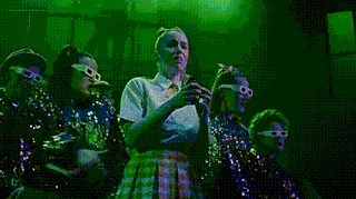 a woman wearing 3d glasses and a sequined jacket talks to another woman