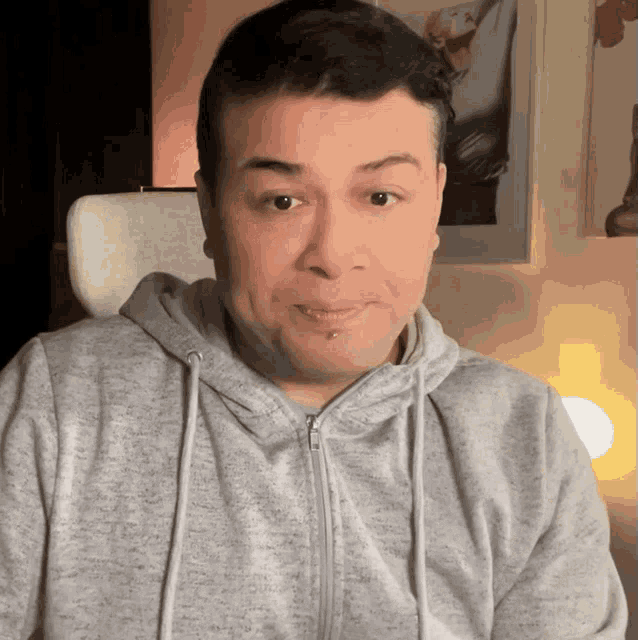 a man wearing a grey hoodie with a zipper
